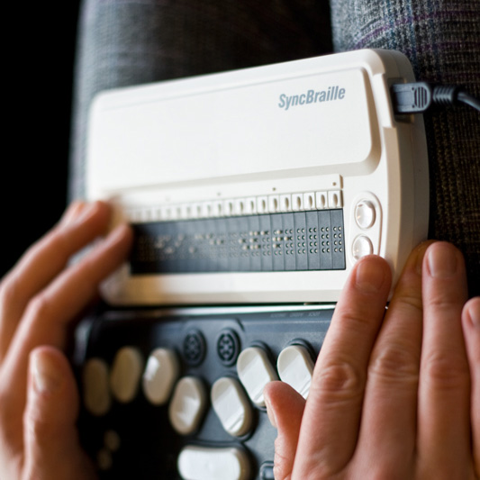 Person using a SyncBraille refreshable braille display